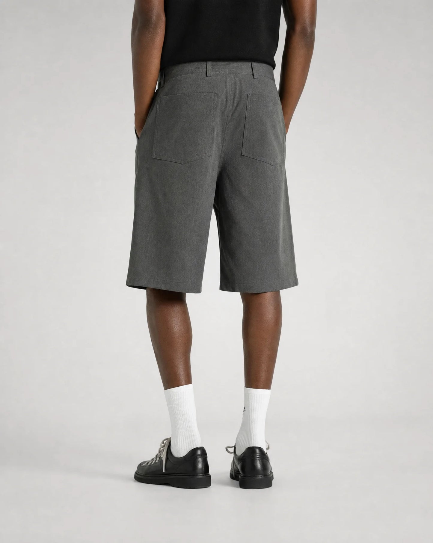 Back view of men's grey baggy bermuda shorts with adjustable waistband, embroidered back pocket and relaxed tailored fit by ILYNORA