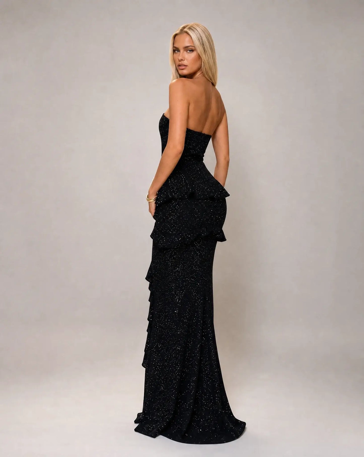Black strapless ruffle maxi dress for women by Ilynora, side view highlighting the flowing fit and textured fabric