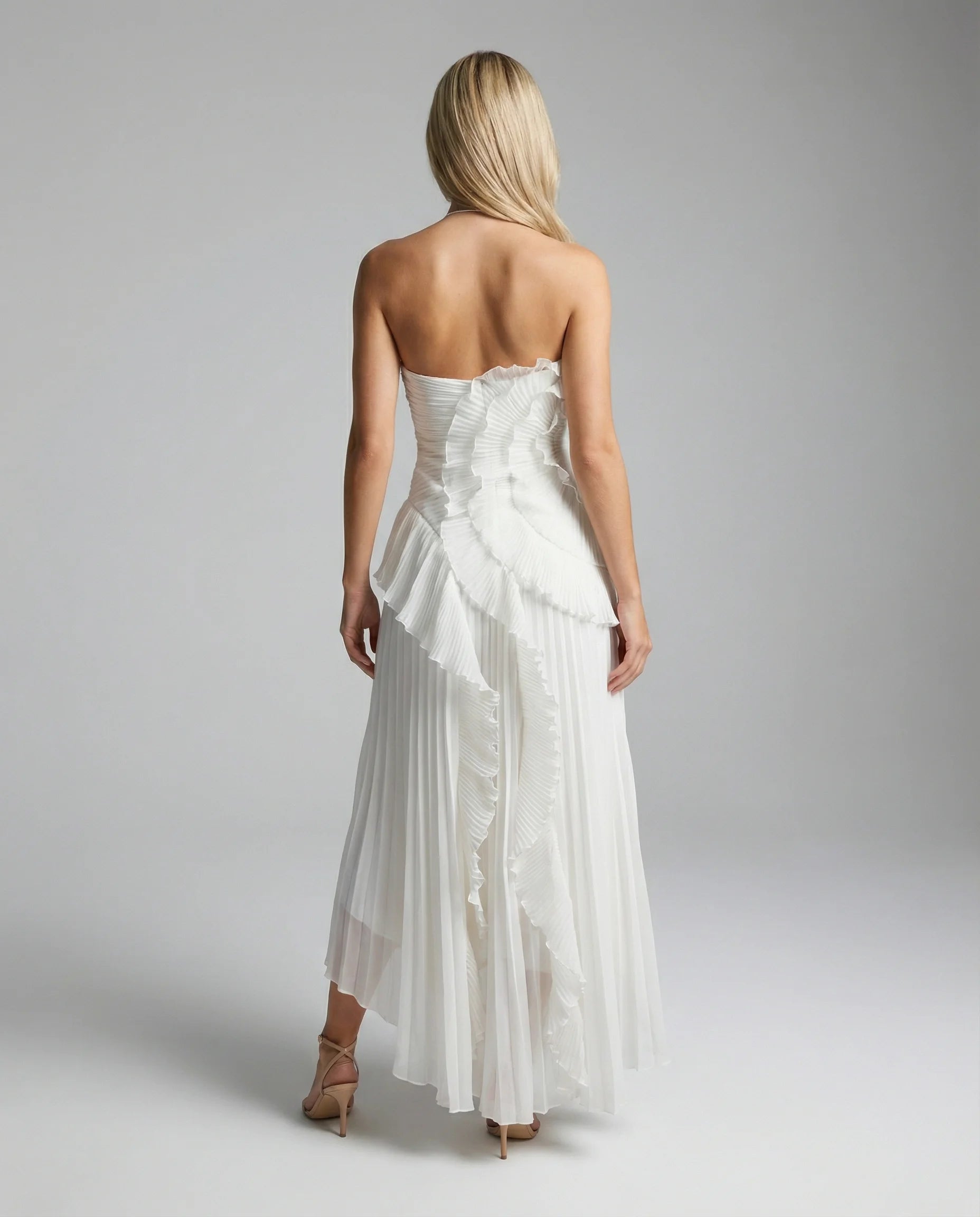 White pleated maxi dress with ruffles by Ilynora, back view with cross-back straps and refined feminine fit