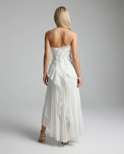 White pleated maxi dress with ruffles by Ilynora, back view with cross-back straps and refined feminine fit