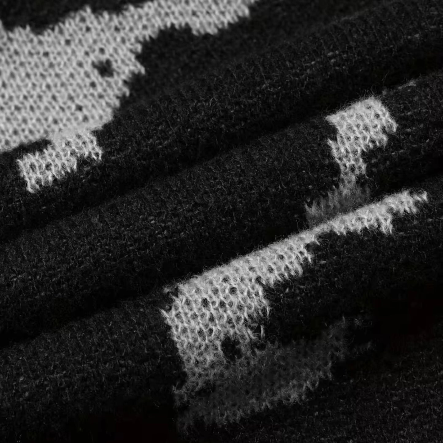 Men's black abstract knit sweater by Ilynora, sleeve detail showing pattern and ribbed cuff