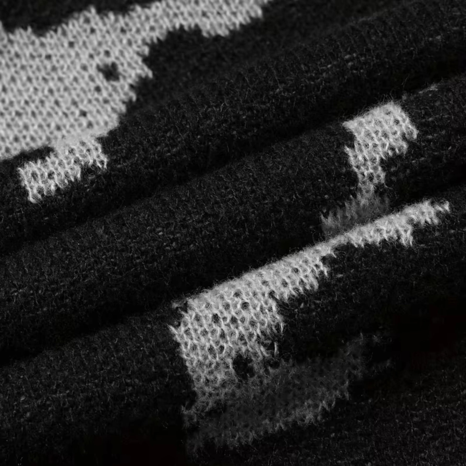 Men's black abstract knit sweater by Ilynora, sleeve detail showing pattern and ribbed cuff