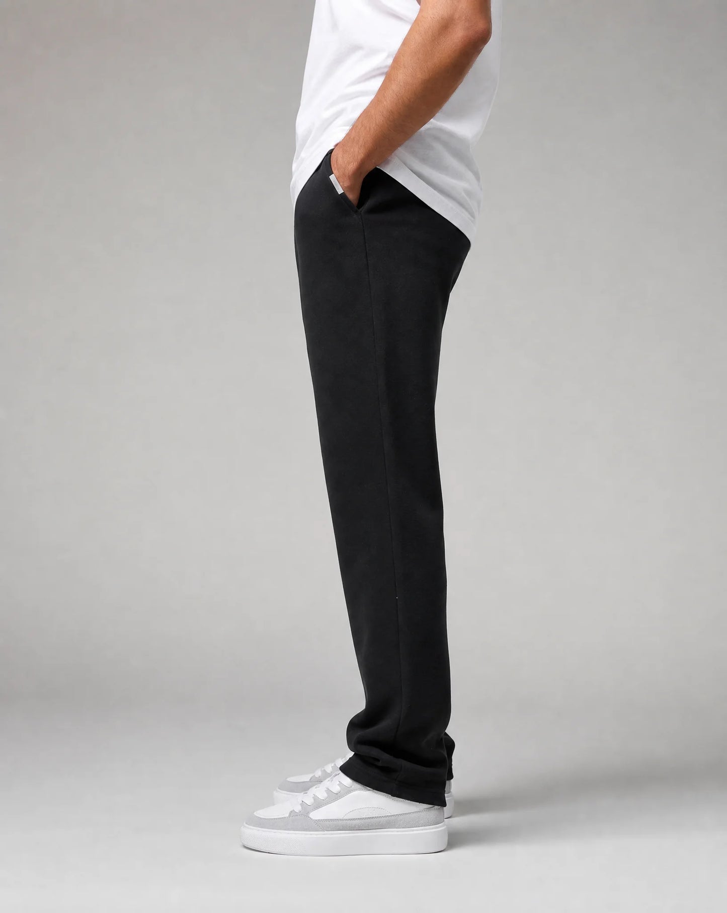 Side view of men's black relaxed fit open hem joggers with concealed side pockets and soft fleece fabric by ILYNORA