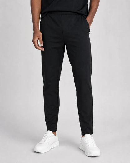 Men's black premium technical pants with soft shell stretch fabric, tapered fit and drawstring waist by ILYNORA