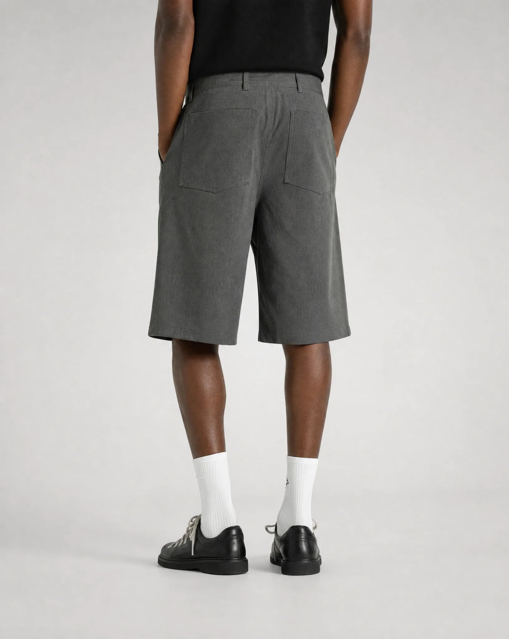 Back view of men's grey baggy bermuda shorts with adjustable waistband, embroidered back pocket and relaxed tailored fit by ILYNORA
