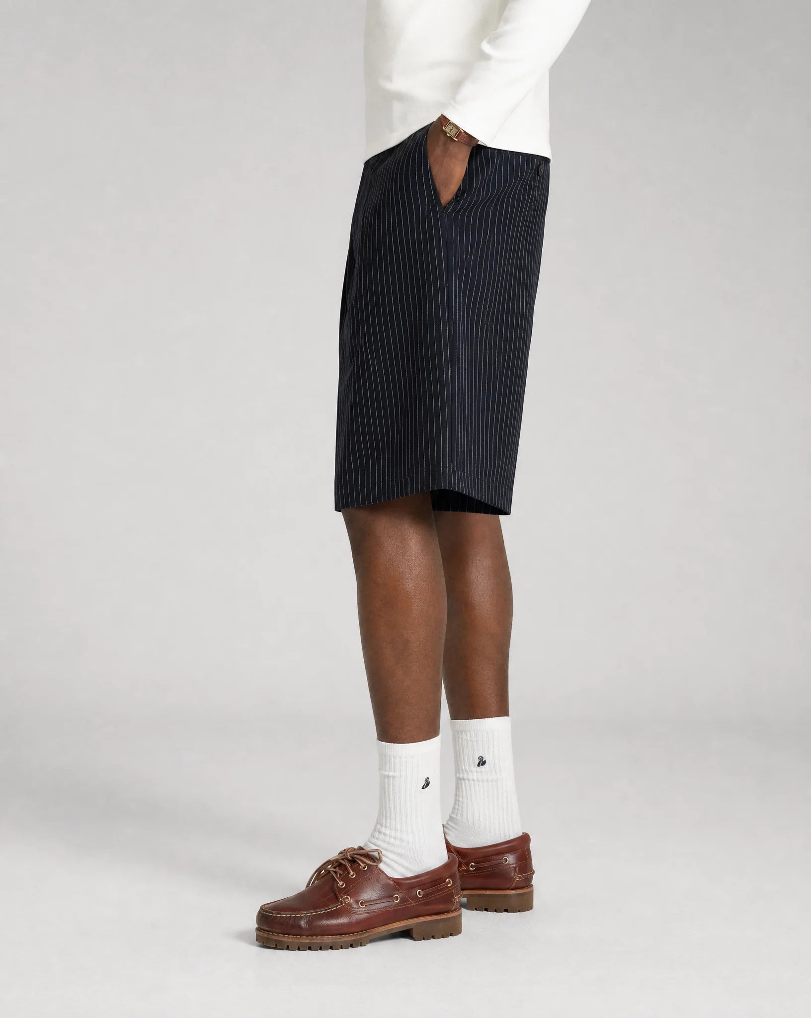 Side view of men's navy pinstriped bermuda shorts with relaxed oversized fit, tailored pleats and adjustable waistband by ILYNORA