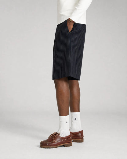 Side view of men's navy pinstriped bermuda shorts with relaxed oversized fit, tailored pleats and adjustable waistband by ILYNORA