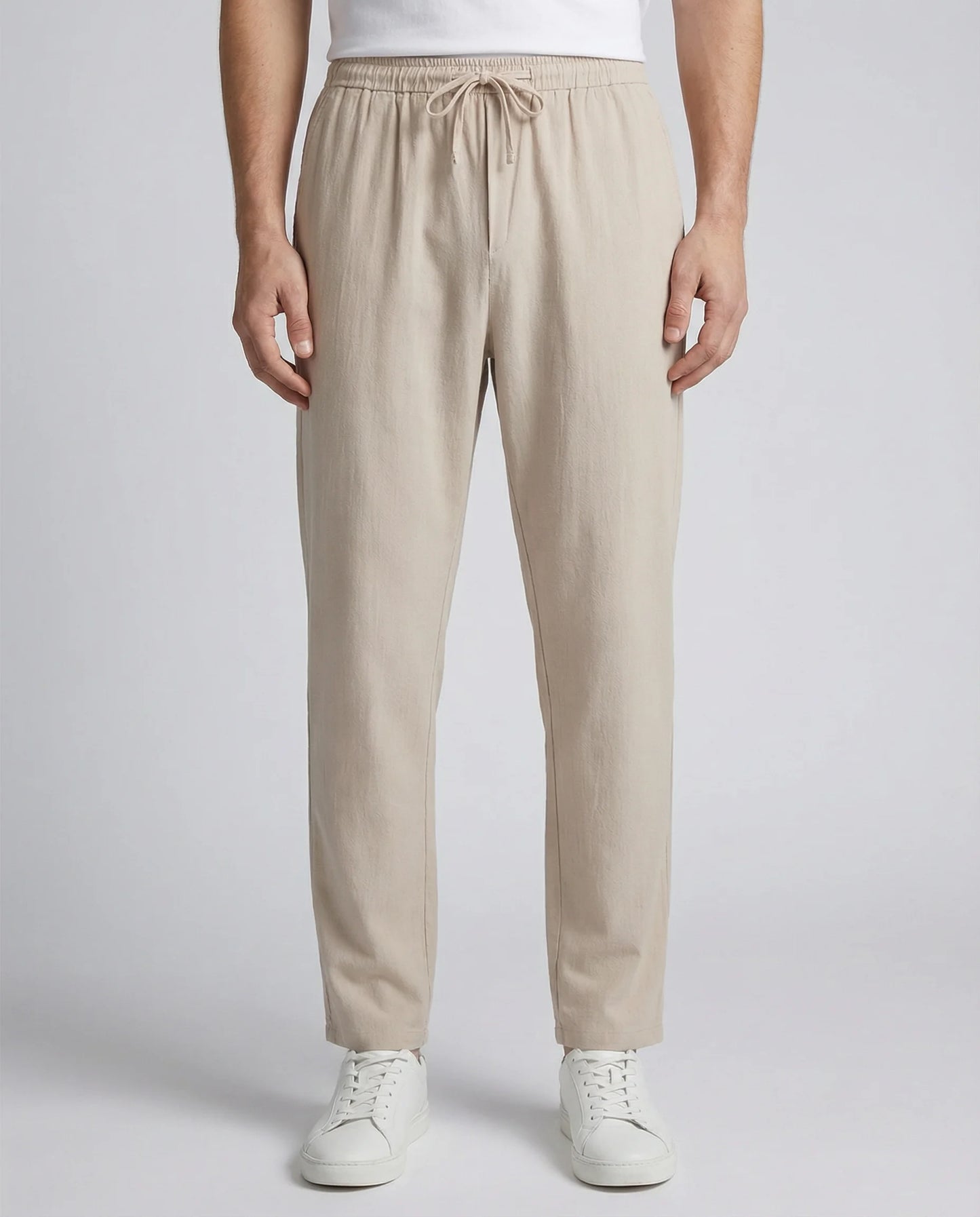 Men's relaxed linen drawstring trousers in beige by Ilynora, front view with elastic waistband and relaxed fit