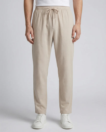 Men's relaxed linen drawstring trousers in beige by Ilynora, front view with elastic waistband and relaxed fit
