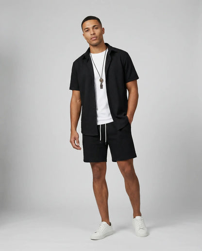 Men's textured shirt and shorts set in black by Ilynora, front view with short sleeve shirt and tailored shorts