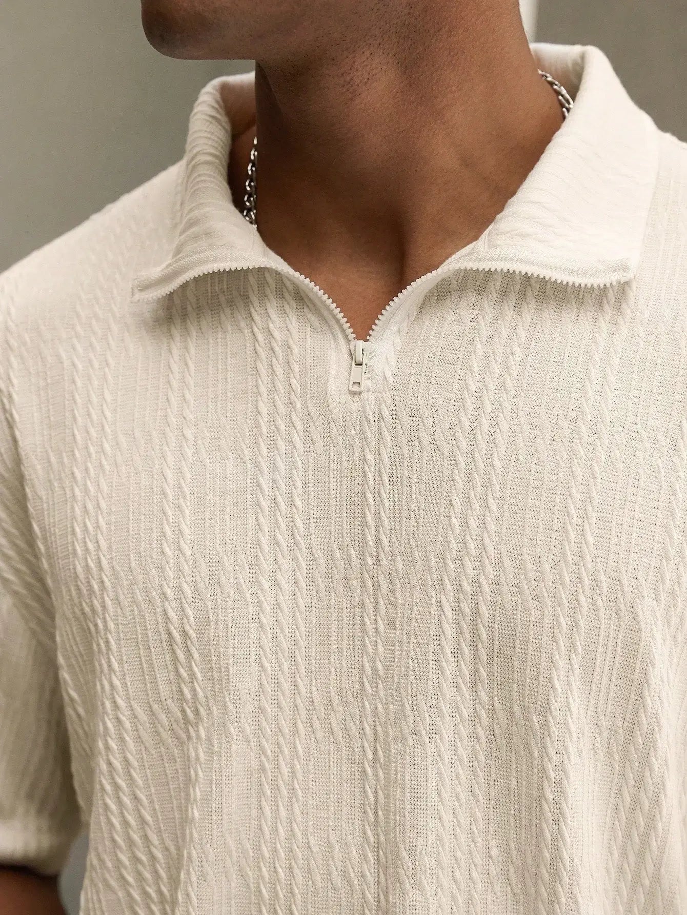 Beige textured polo set by Ilynora, close-up showing zip collar and fabric texture