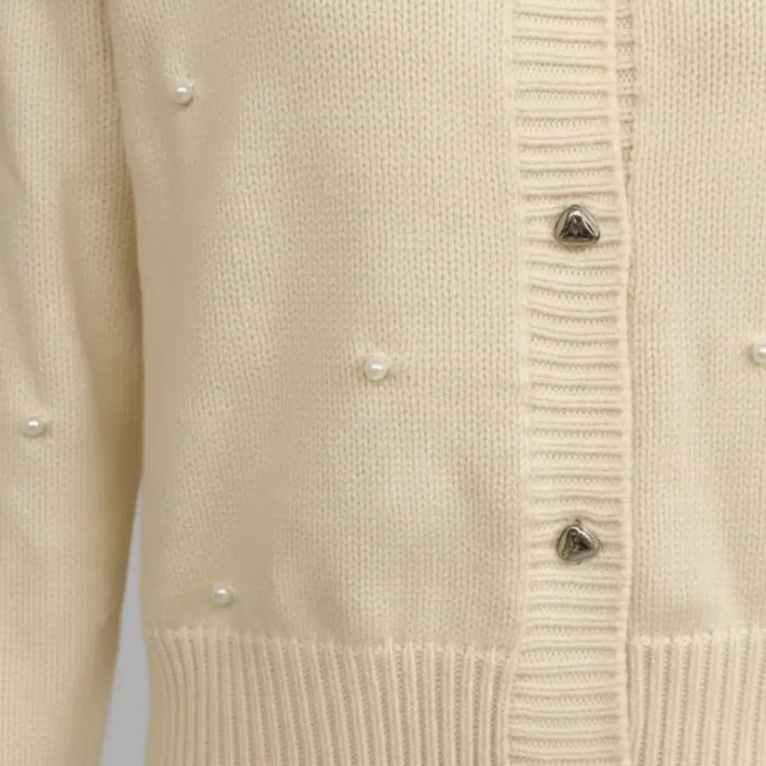 Cream knit cardigan detail by Ilynora, close-up of pearl embellishments and ribbed finish