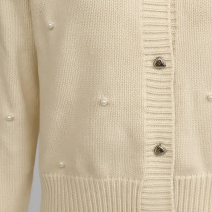Cream knit cardigan detail by Ilynora, close-up of pearl embellishments and ribbed finish