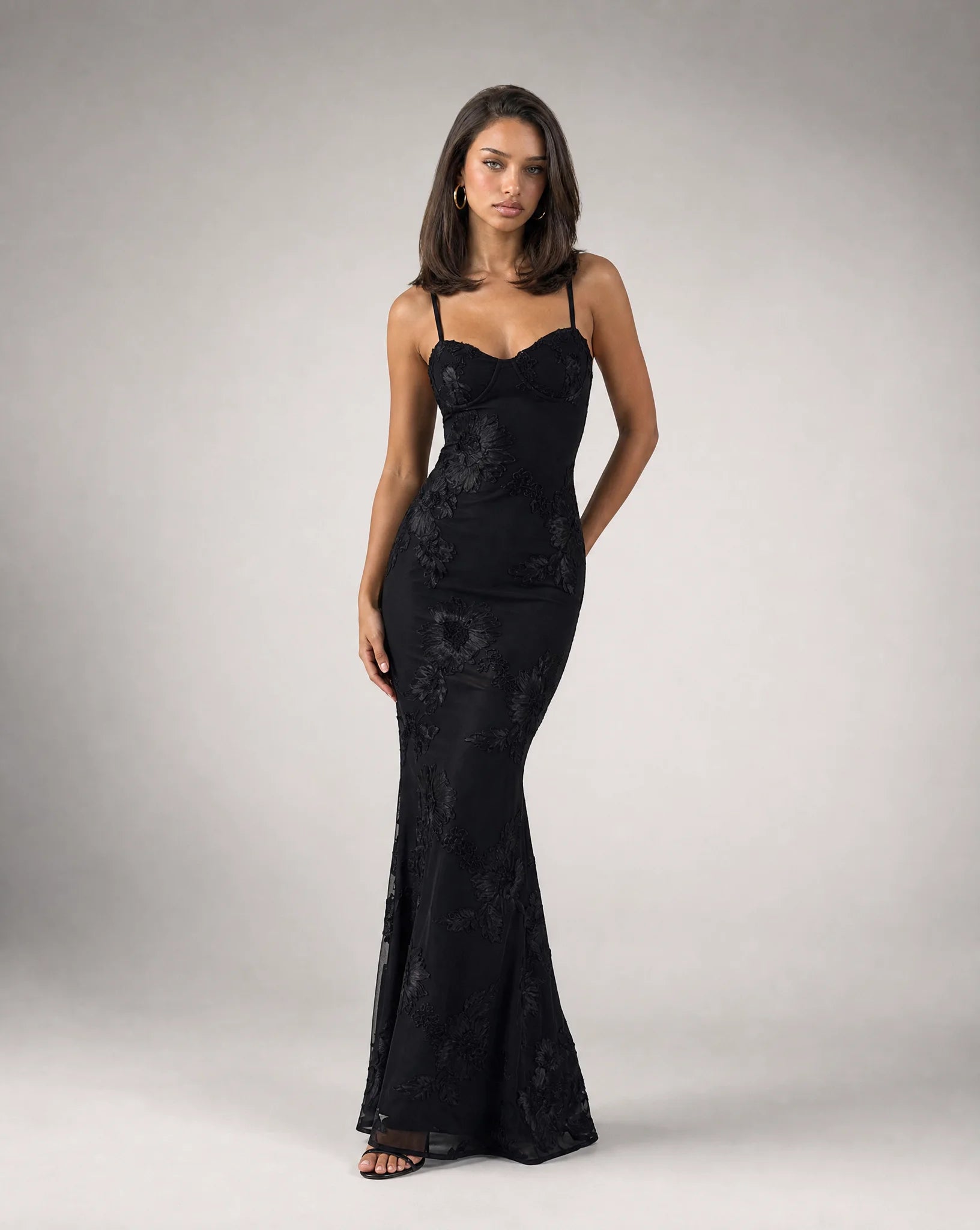 Black open back lace maxi dress for women by Ilynora, angled view highlighting the fitted silhouette and lace detail