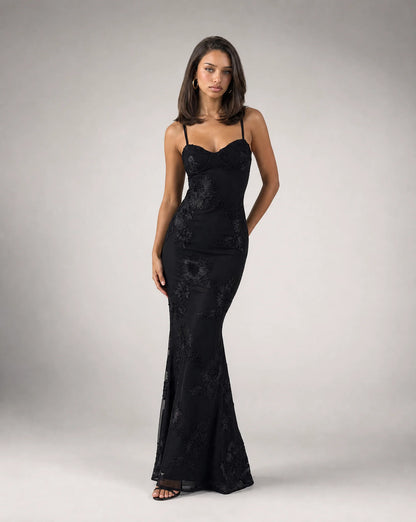 Black open back lace maxi dress for women by Ilynora, angled view highlighting the fitted silhouette and lace detail