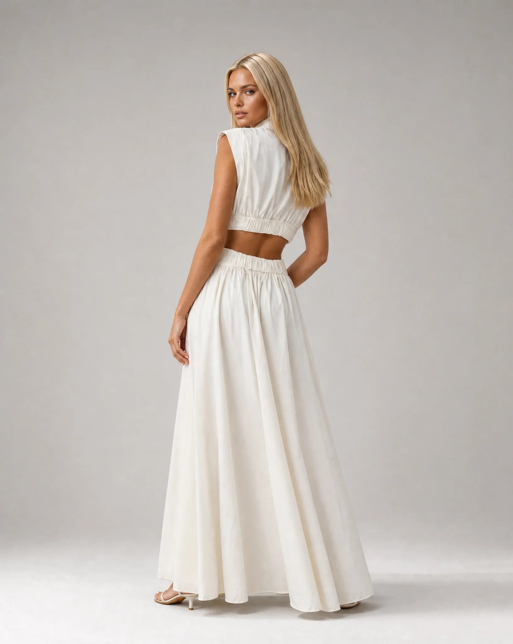 White sleeveless cut out maxi dress for women by Ilynora, side view highlighting the waist detail and flowing fit