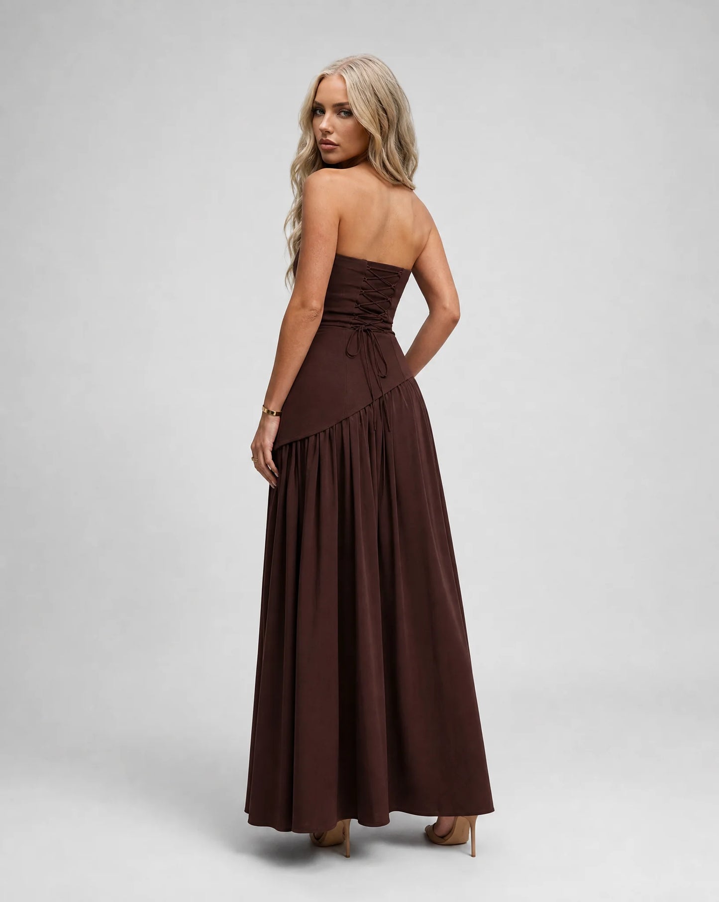 Brown strapless maxi dress for women by Ilynora, angled back view highlighting the elegant drape and open back