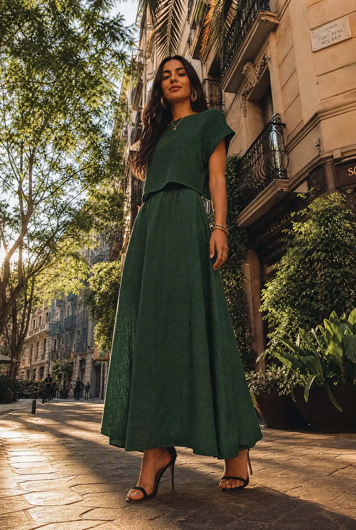 Woman wearing a green linen co-ord set with a cropped top and flowy maxi skirt, styled with black strappy heels