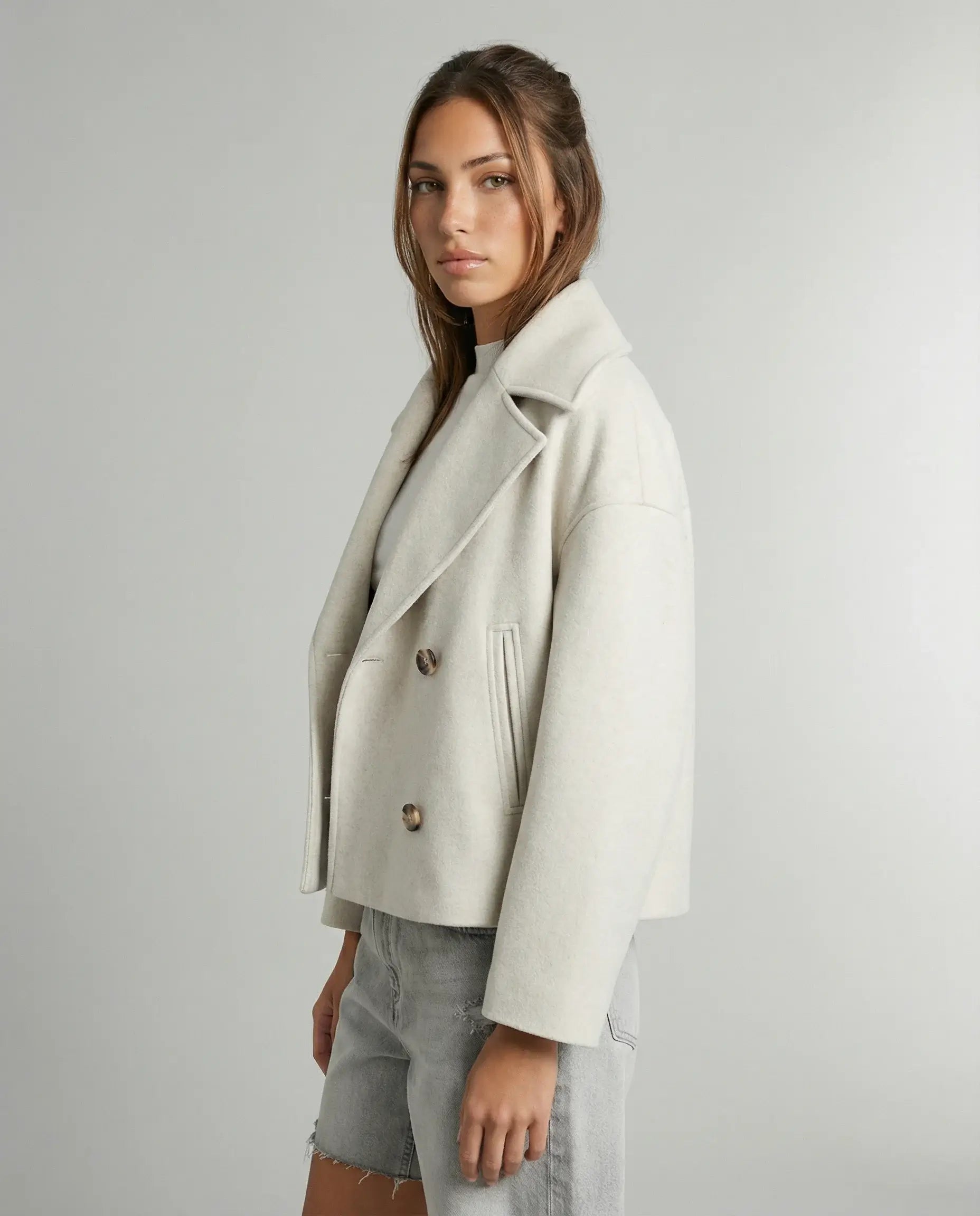 Double-breasted cropped jacket in white by Ilynora, close-up highlighting buttons and refined details
