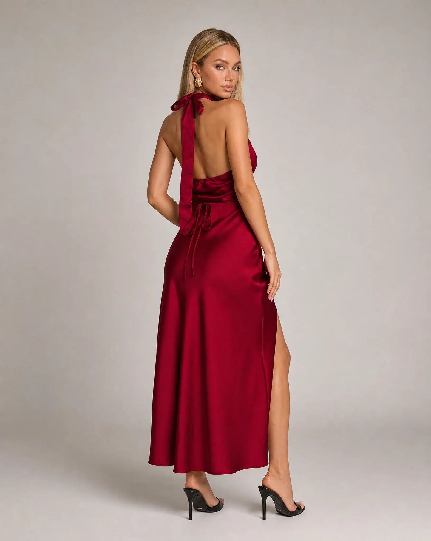 Red halterneck satin maxi dress for women by Ilynora, full length view highlighting the fluid fit and leg split