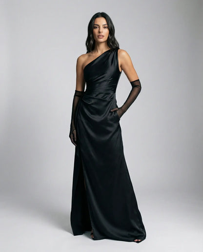 Women's one-shoulder satin maxi dress in black by Ilynora, front view with high slit and refined silhouette