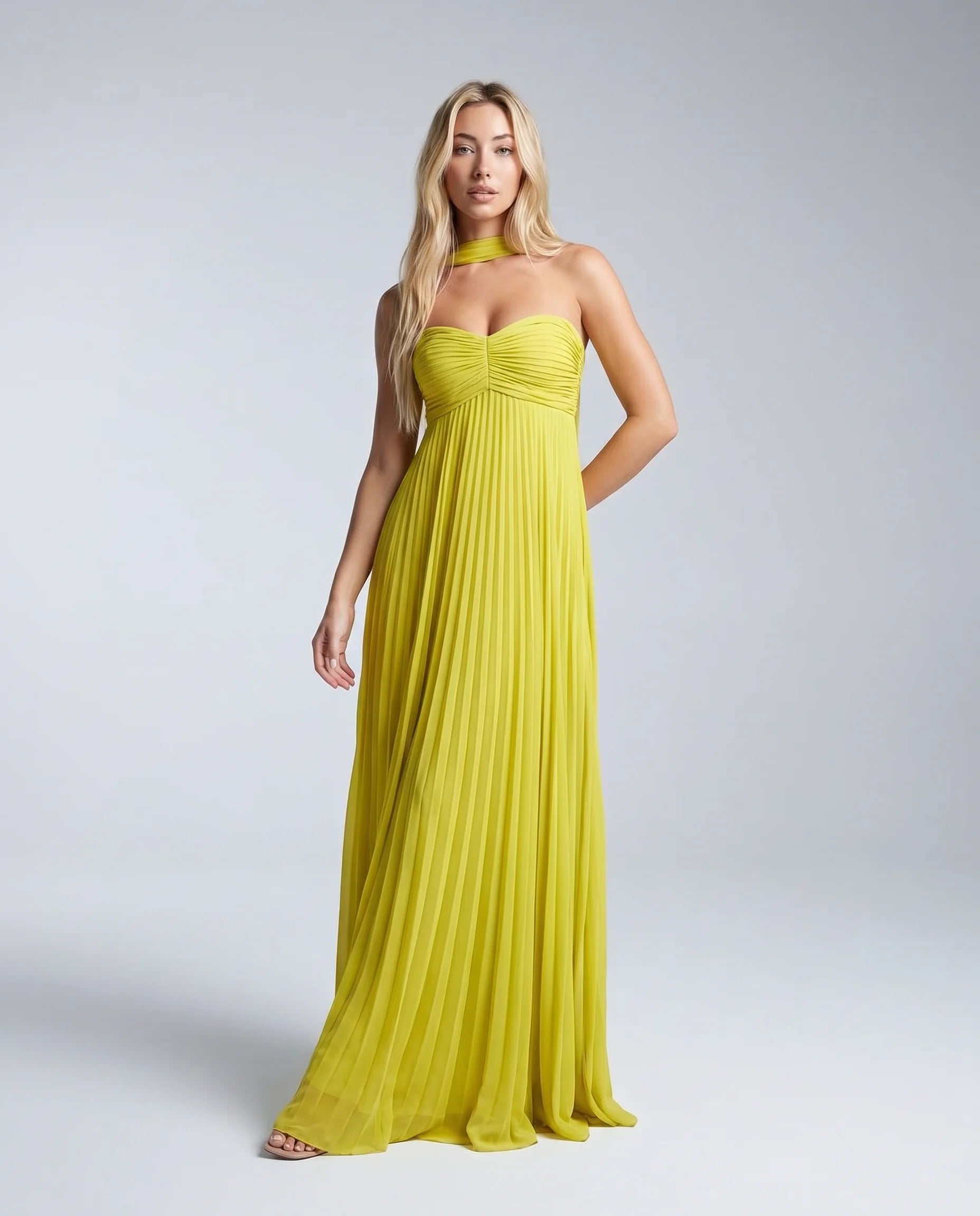Woman wearing a yellow pleated halter maxi dress with sweetheart neckline and flowing skirt