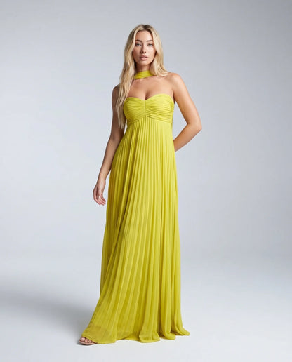 Woman wearing a yellow pleated halter maxi dress with sweetheart neckline and flowing skirt