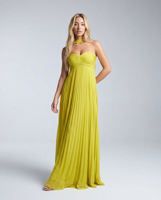 Woman wearing a yellow pleated halter maxi dress with sweetheart neckline and flowing skirt