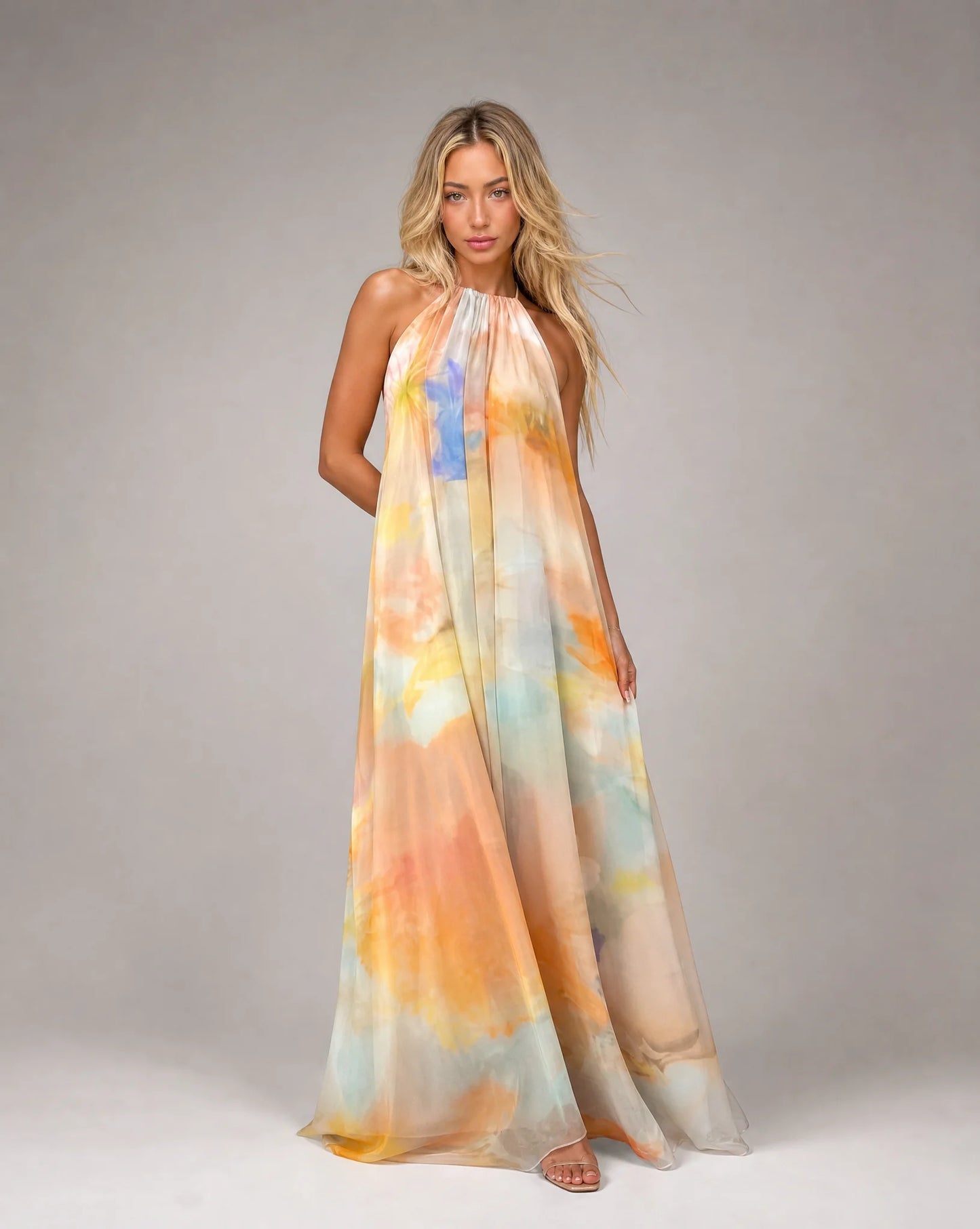 Orange printed halter maxi dress with flowing silhouette and soft watercolour pattern by ILYNORA