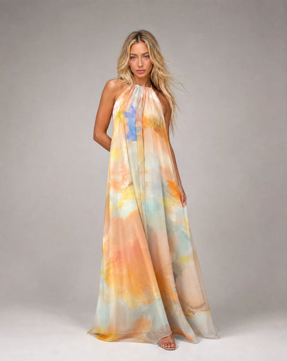 Orange printed halter maxi dress with flowing silhouette and soft watercolour pattern by ILYNORA