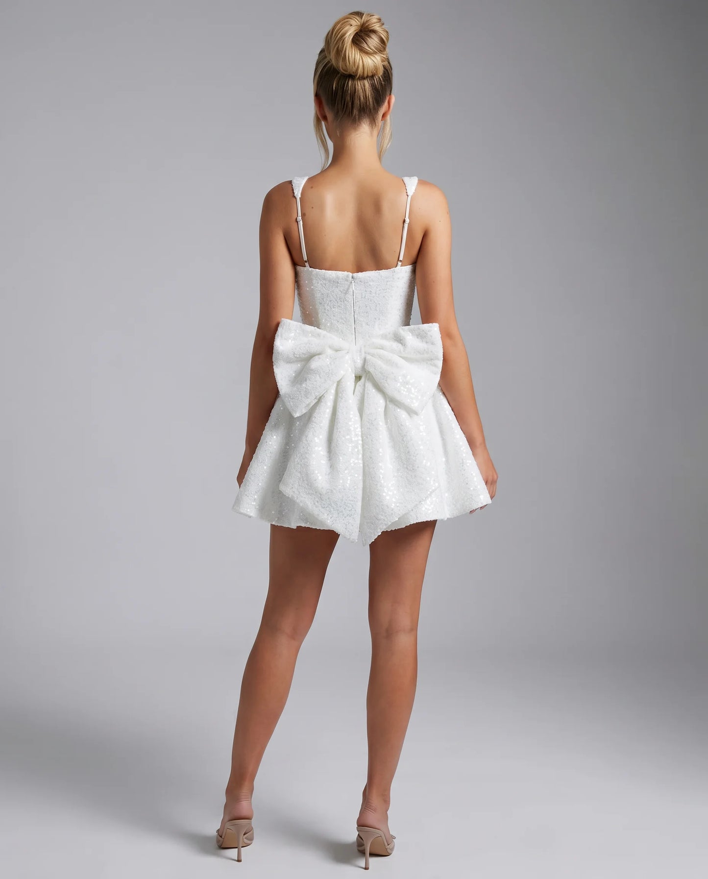 White sequin bow mini dress back view with oversized bow detail and elegant fit and flare silhouette by ILYNORA