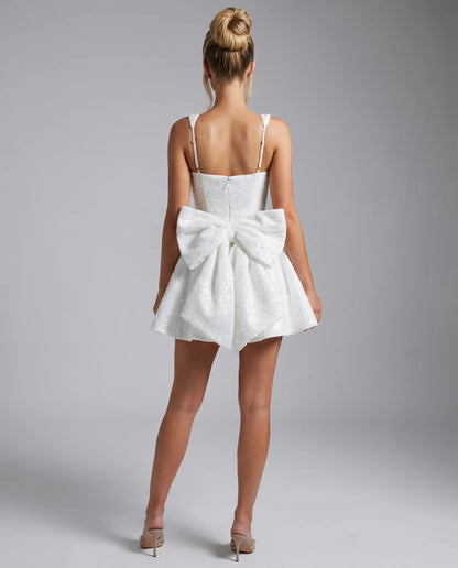 White sequin bow mini dress back view with oversized bow detail and elegant fit and flare silhouette by ILYNORA