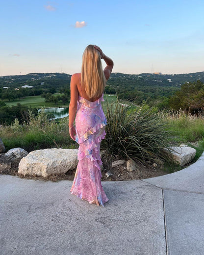 Woman wearing ILYNORA pink floral ruffle maxi dress with flowing skirt and feminine open-back silhouette