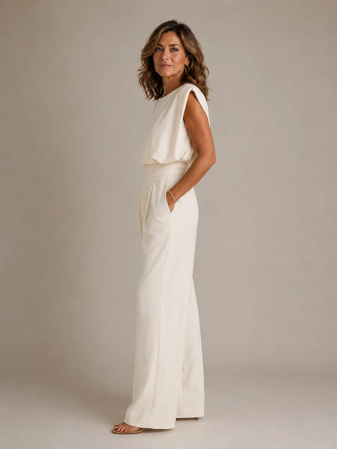 Side view of women's golden sleeveless wide leg jumpsuit with elegant pleated trousers, flowing silhouette and tailored fit by ILYNORA
