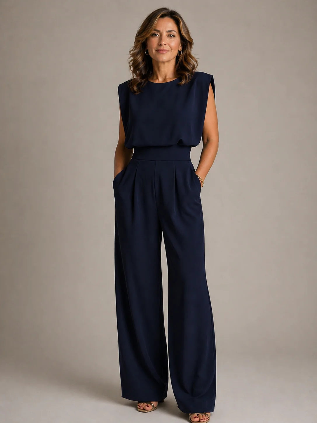 Women's navy sleeveless pleated wide leg jumpsuit with elegant draped bodice, tailored waist and flowing evening silhouette by ILYNORA
