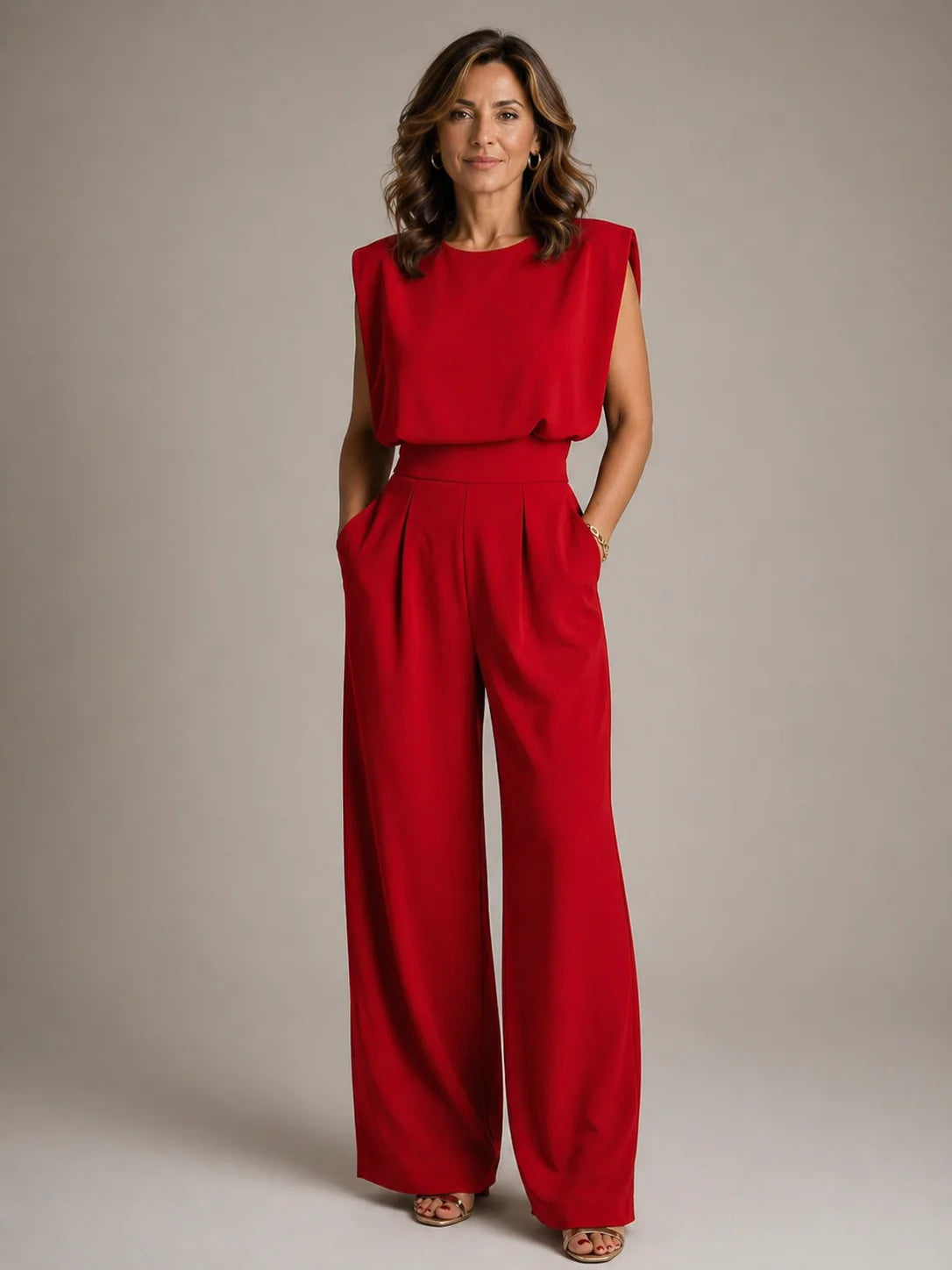 Women's red sleeveless pleated wide leg jumpsuit with flowing trousers, draped bodice and elegant formal occasion styling by ILYNORA